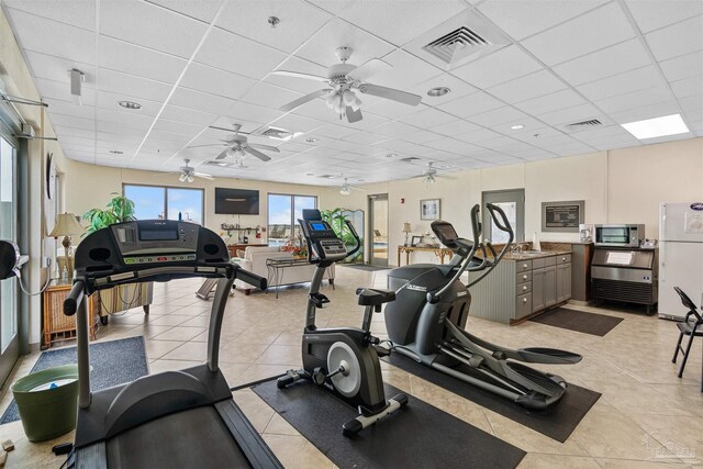 exercise room with light tile patterned flooring, a paneled ceiling, and ceiling fan