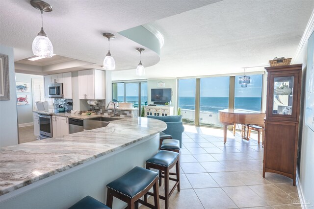 kitchen featuring a breakfast bar, tasteful backsplash, white cabinets, stainless steel appliances, and sink