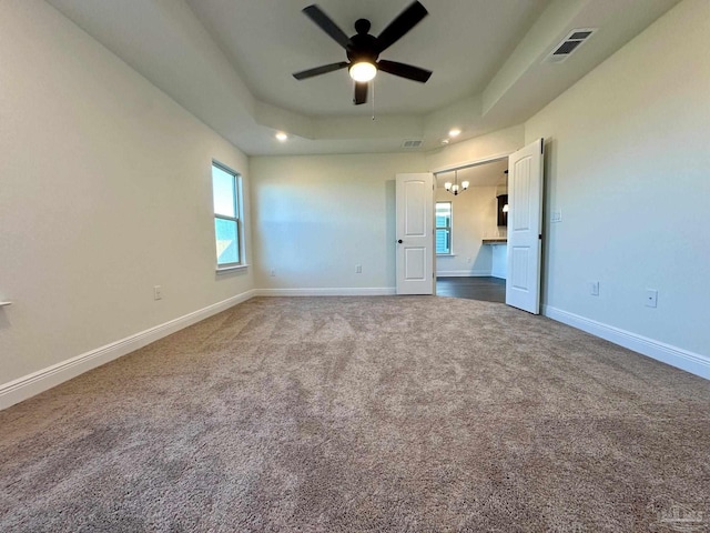 unfurnished bedroom with ceiling fan, carpet floors, and a tray ceiling