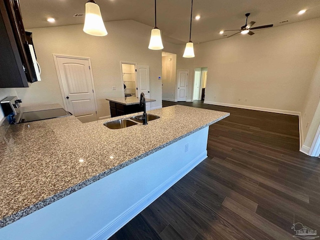 kitchen featuring pendant lighting, dark wood-type flooring, black range, sink, and light stone countertops