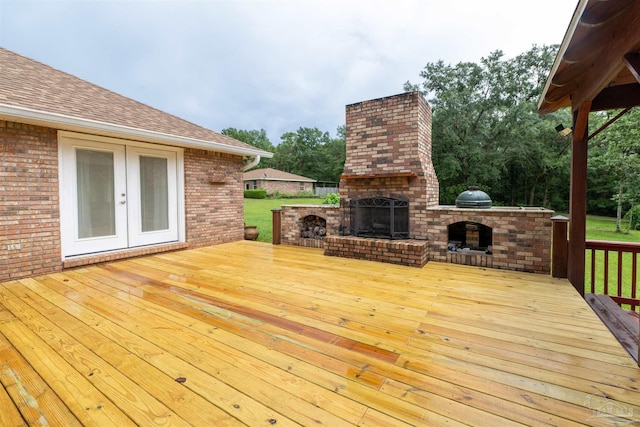 deck with an outdoor brick fireplace, french doors, and a lawn