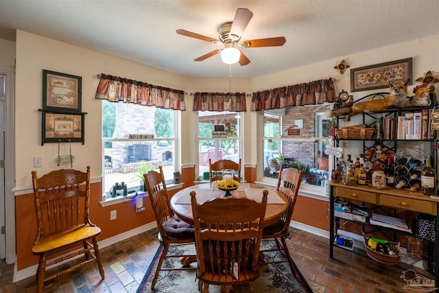 dining space with brick floor, baseboards, a textured ceiling, and ceiling fan
