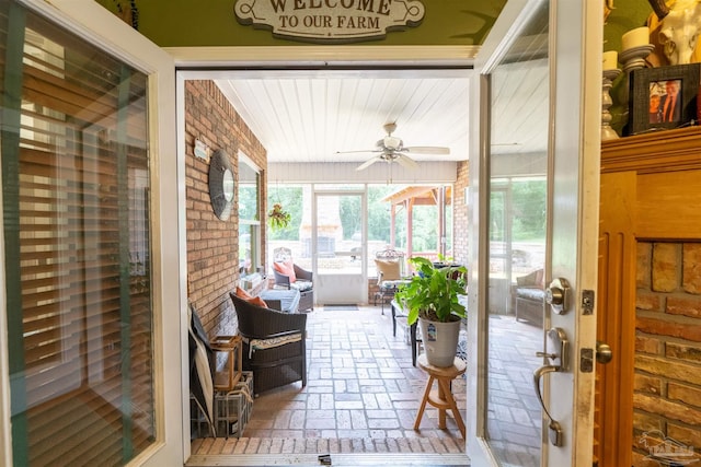 sunroom featuring brick floor and ceiling fan