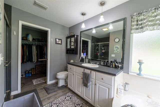 full bath with a walk in closet, vanity, visible vents, and wood finished floors