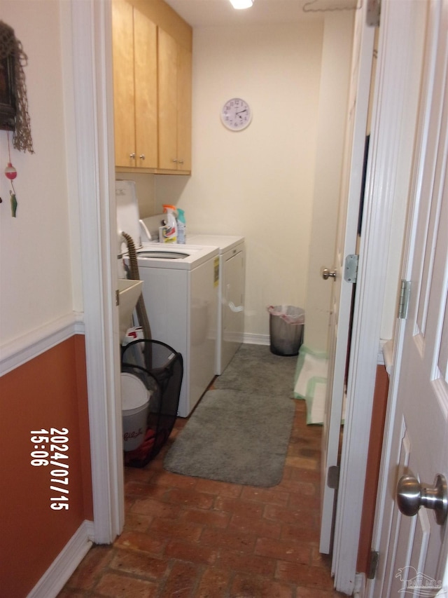 laundry area featuring cabinet space, independent washer and dryer, brick floor, and baseboards