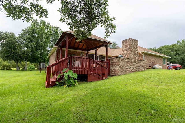 rear view of property with a gazebo, a yard, brick siding, and a chimney
