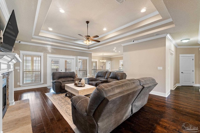 living room with dark hardwood / wood-style floors, a raised ceiling, crown molding, and a premium fireplace