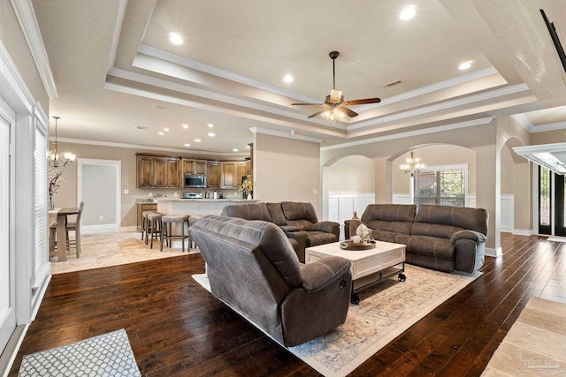 living room with ornamental molding, a raised ceiling, and dark wood-type flooring