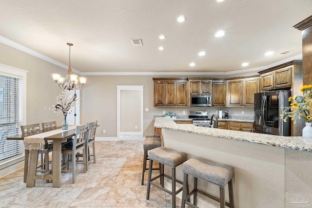 kitchen featuring light stone countertops, appliances with stainless steel finishes, ornamental molding, a breakfast bar, and pendant lighting