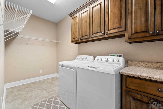 laundry room with washer and dryer, light tile patterned floors, a textured ceiling, and cabinets