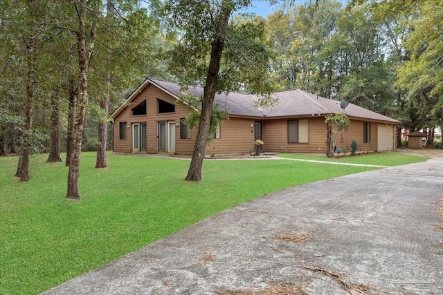 ranch-style house featuring driveway, an attached garage, and a front yard