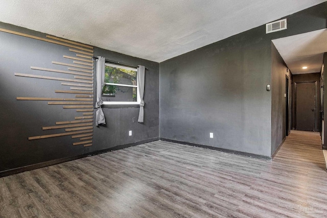 unfurnished room featuring a textured ceiling and wood-type flooring