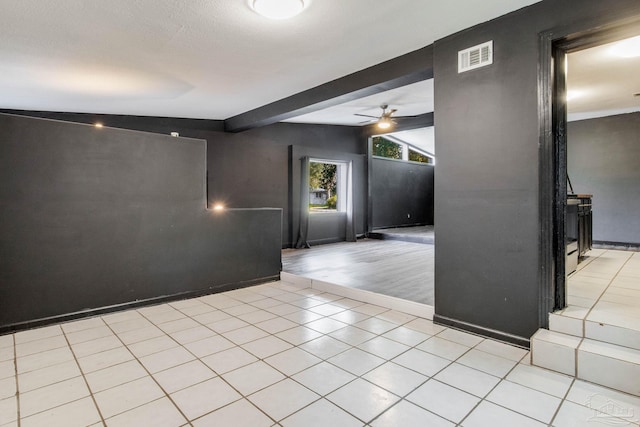 tiled empty room featuring vaulted ceiling with beams and ceiling fan