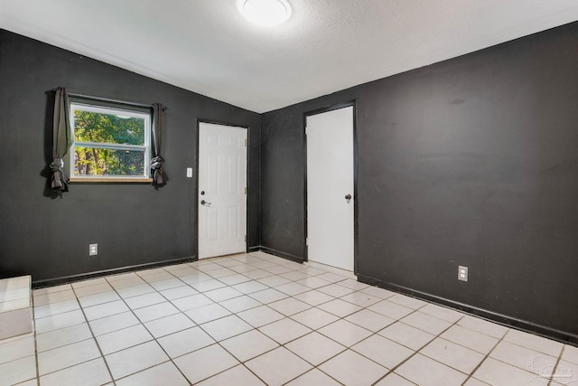 tiled spare room with lofted ceiling and a textured ceiling