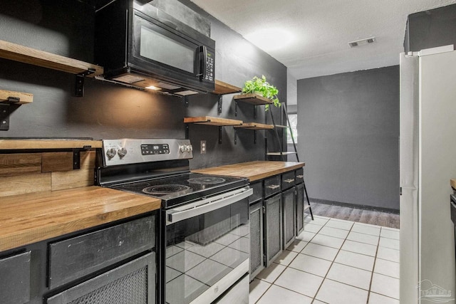 kitchen with electric stove, light tile patterned flooring, decorative backsplash, and butcher block counters