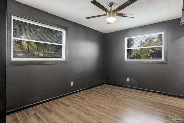 empty room with ceiling fan, hardwood / wood-style flooring, and a healthy amount of sunlight