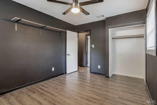 unfurnished bedroom with dark hardwood / wood-style floors, ceiling fan, and a closet