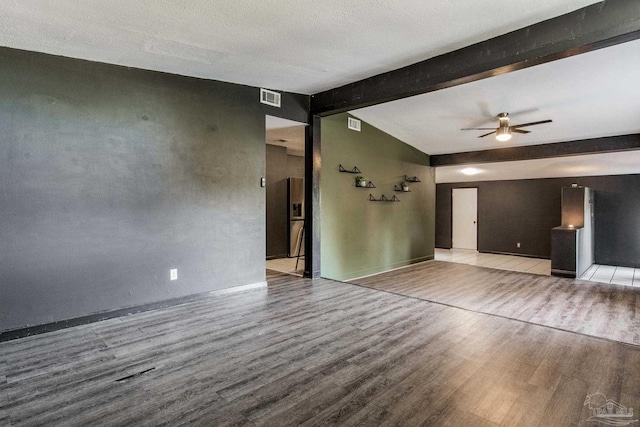 unfurnished living room with ceiling fan, a textured ceiling, beam ceiling, and hardwood / wood-style floors