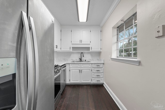 kitchen with a textured ceiling, stainless steel appliances, white cabinetry, ornamental molding, and sink