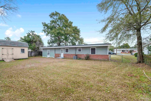 rear view of property featuring a yard, central air condition unit, and a storage shed