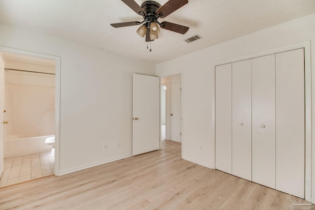 8500 Blue Jay Way, Pensacola, FL 32534 - unfurnished bedroom featuring light wood-style floors, ensuite bath, a closet, a textured ceiling, and ceiling fan