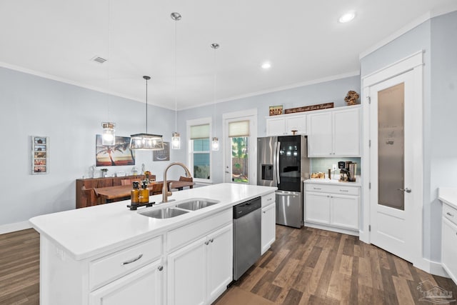 kitchen featuring appliances with stainless steel finishes, white cabinetry, an island with sink, decorative light fixtures, and sink