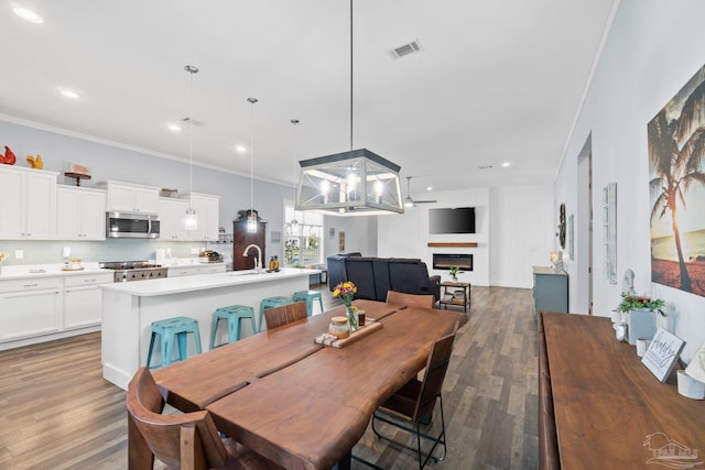 dining room featuring sink, dark hardwood / wood-style floors, and crown molding