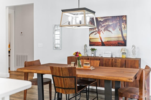 dining area with hardwood / wood-style flooring and a notable chandelier