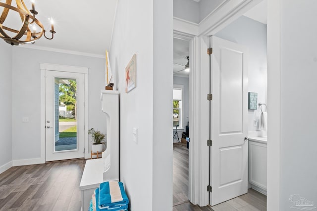 foyer entrance featuring light hardwood / wood-style flooring, an inviting chandelier, and crown molding