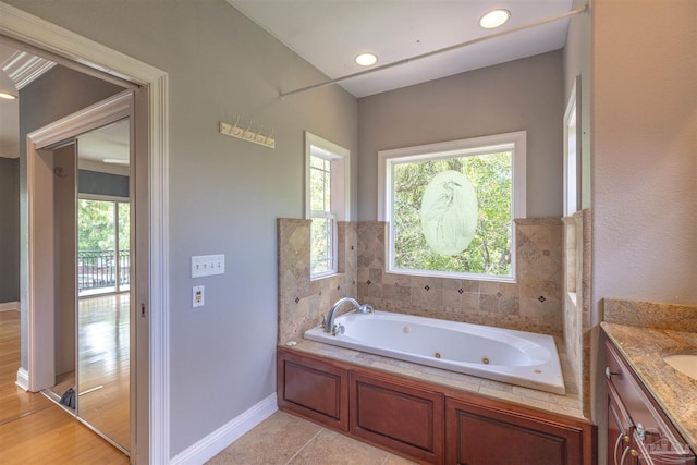 bathroom featuring tile patterned flooring, vanity, a tub, and a healthy amount of sunlight