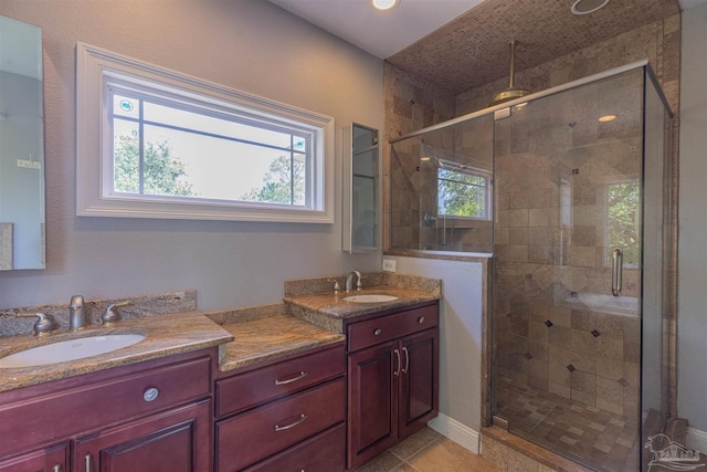 bathroom featuring tile patterned flooring, vanity, plenty of natural light, and a shower with shower door