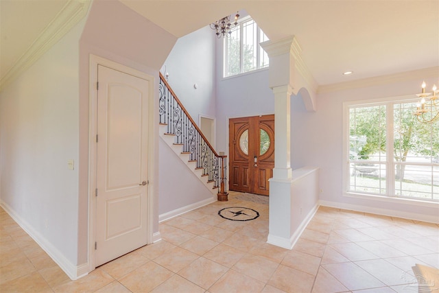 tiled foyer with an inviting chandelier, ornamental molding, and ornate columns