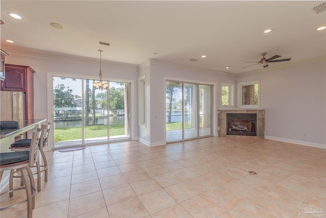 unfurnished living room with a water view, a fireplace, crown molding, and light tile patterned flooring