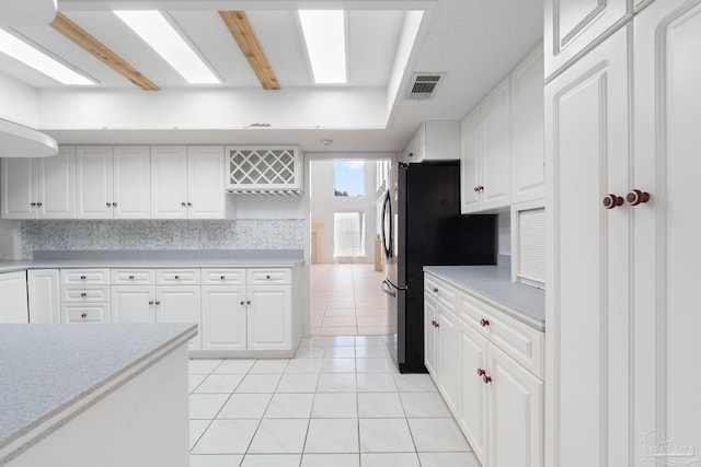 kitchen featuring stainless steel fridge, white cabinetry, and light tile patterned floors