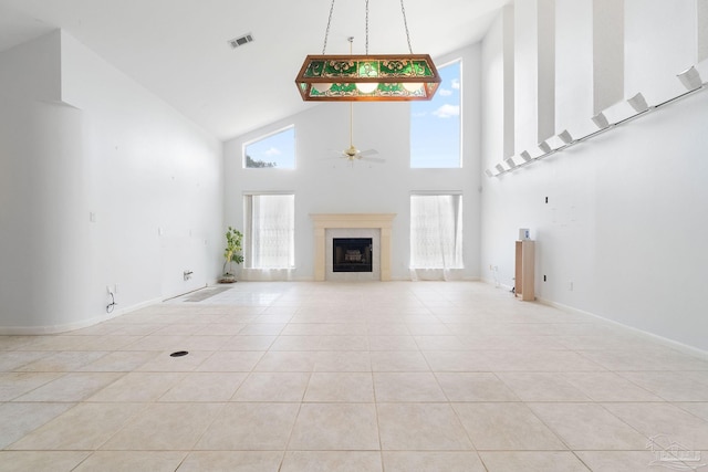 unfurnished living room with ceiling fan, light tile patterned floors, and high vaulted ceiling