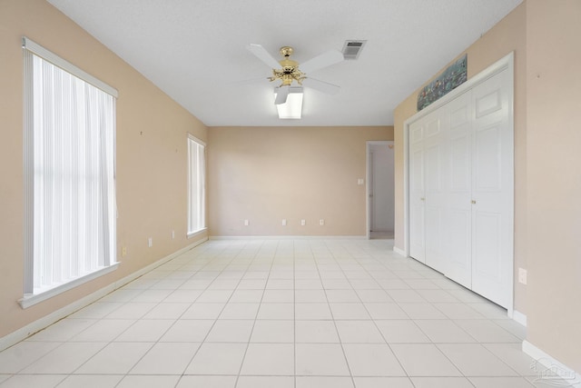 tiled spare room featuring plenty of natural light and ceiling fan