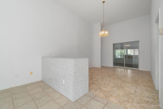 tiled spare room with a chandelier