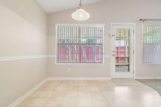 tiled empty room featuring lofted ceiling