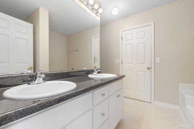 bathroom featuring double vanity, a textured ceiling, a bathtub, and tile patterned floors