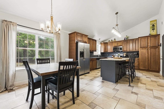4793 Coronado Cir, Crestview, FL 32539 - kitchen featuring stainless steel appliances, a chandelier, a kitchen island, vaulted ceiling, and a breakfast bar