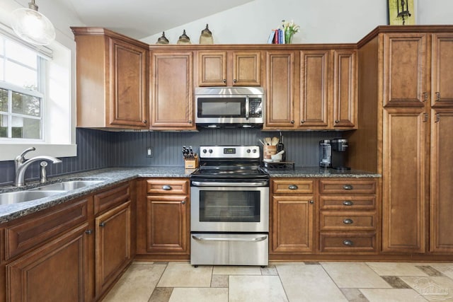 4793 Coronado Cir, Crestview, FL 32539 - kitchen featuring appliances with stainless steel finishes, a sink, brown cabinetry, and vaulted ceiling