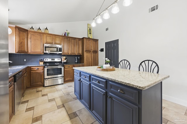 4793 Coronado Cir, Crestview, FL 32539 - kitchen with appliances with stainless steel finishes, decorative backsplash, high vaulted ceiling, a kitchen island, and light stone counters