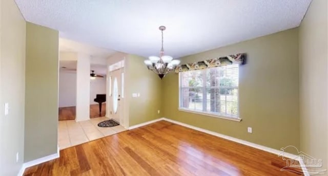 spare room with baseboards, a chandelier, and wood finished floors