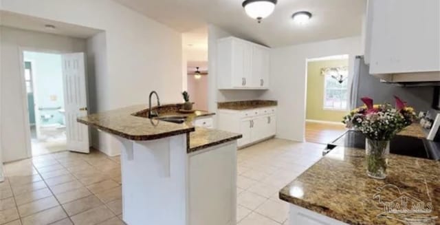 kitchen with light tile patterned flooring, white cabinetry, stone countertops, and a breakfast bar area