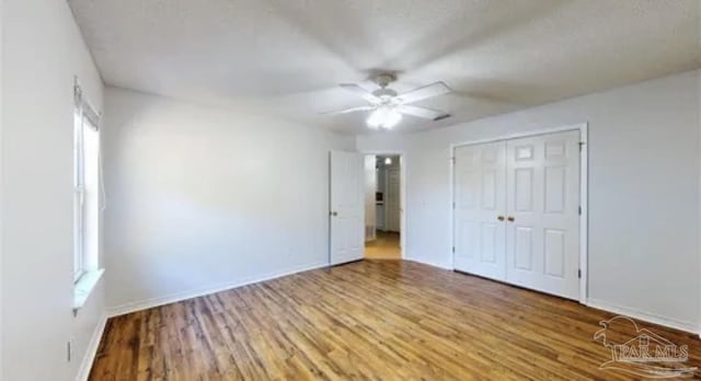 unfurnished bedroom with a ceiling fan, baseboards, a closet, and wood finished floors