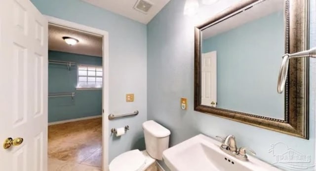 bathroom featuring visible vents, toilet, and a sink