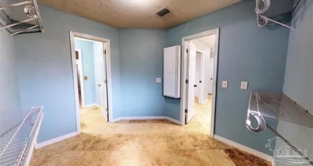 bathroom with baseboards, visible vents, and a textured ceiling
