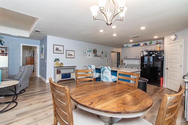 dining area with light hardwood / wood-style floors and an inviting chandelier