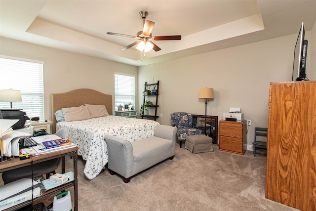 bedroom featuring a raised ceiling, carpet flooring, and ceiling fan