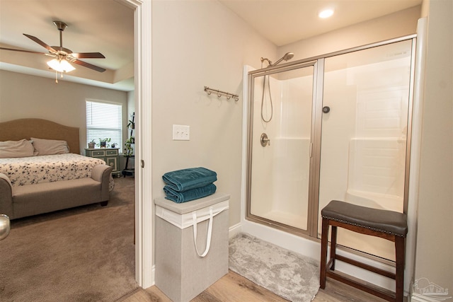 bathroom with ceiling fan, hardwood / wood-style flooring, and a shower with door